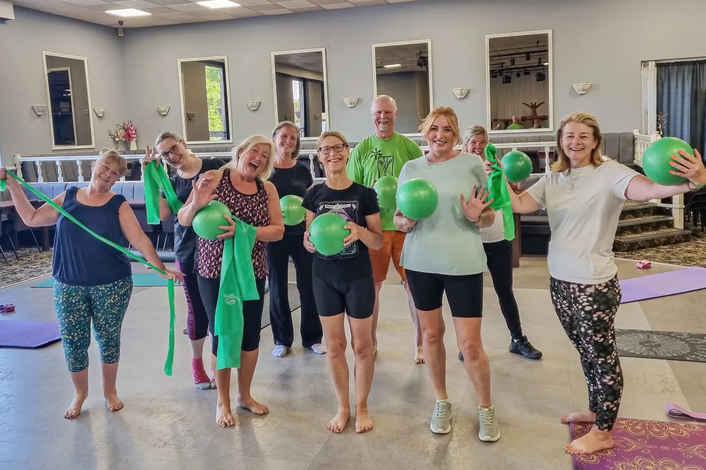 A mixed-age Start Right Pilates class smiling with resistance bands and Pilates balls