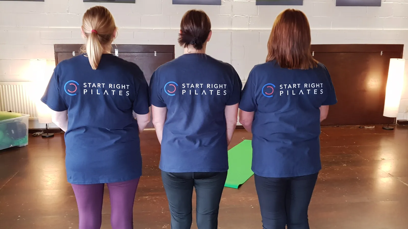 Three women wearing Start Right Pilates branded shirts in the studio